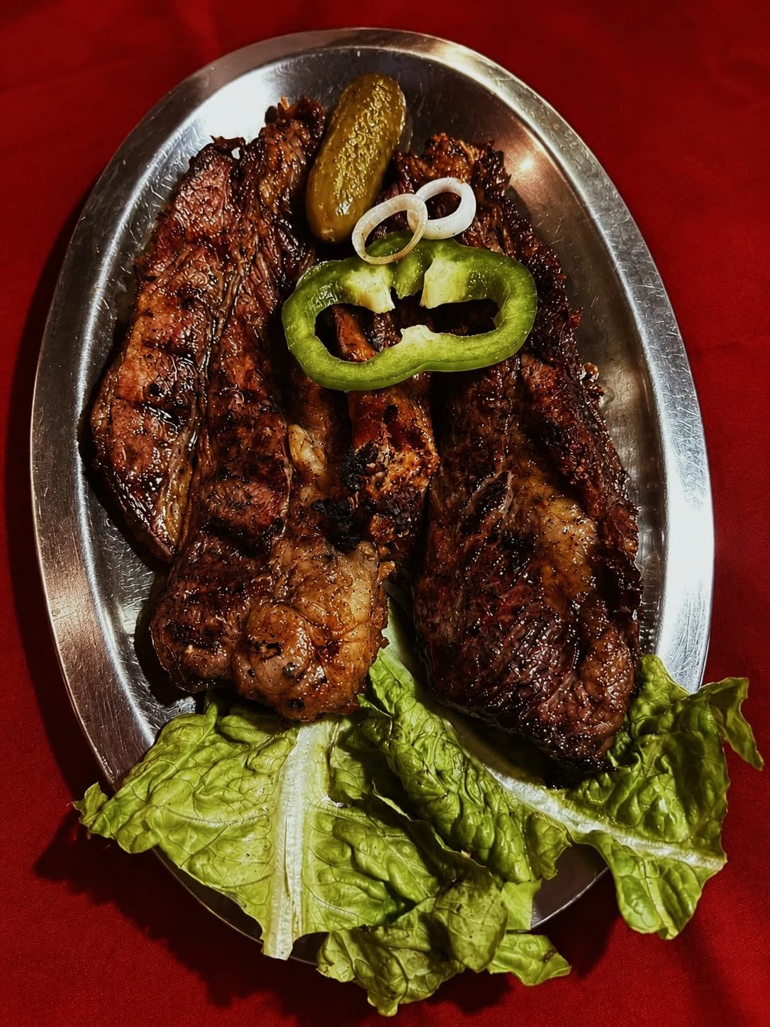 Carne a la parrilla servida en una fuente con guarnición fresca
