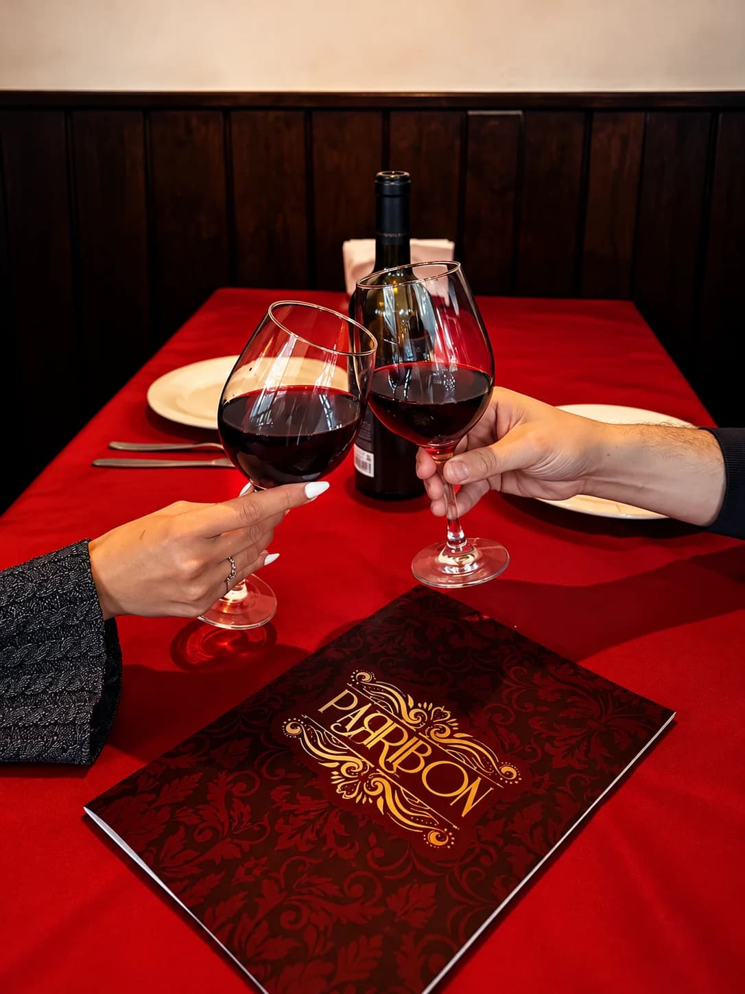 Brindis con vino tinto sobre una mesa con la carta de Parribón
